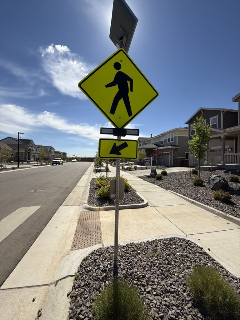 Solar-powered pedestrian crossing sign on a new residential street