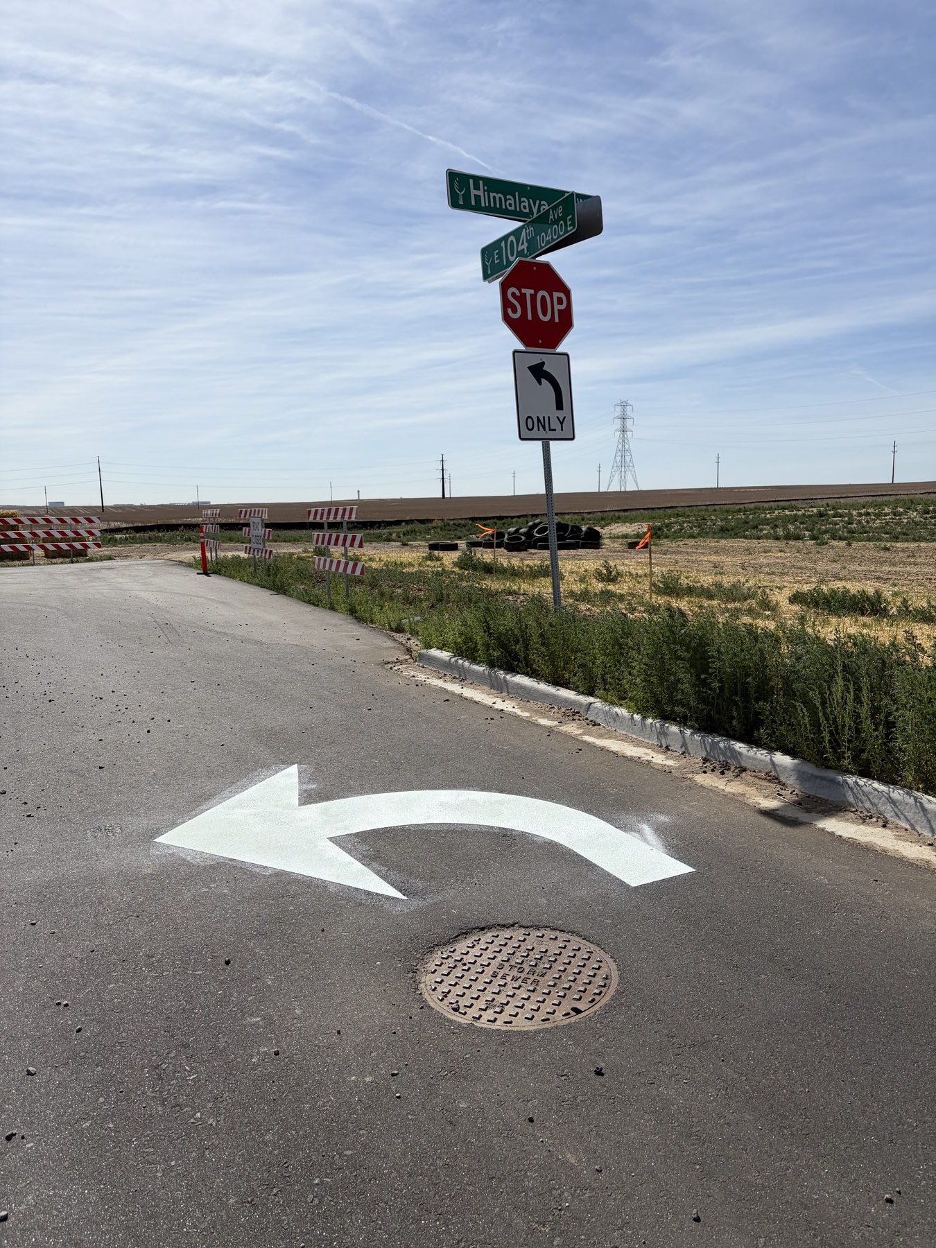 STOP sign with Himalaya and E 104th Ave street-name blades and a left-turn pavement arrow